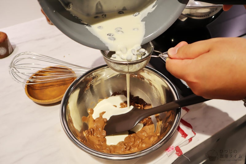 沸騰させた生クリームを、コーヒー豆を取り除きながらチョコレートに入れる